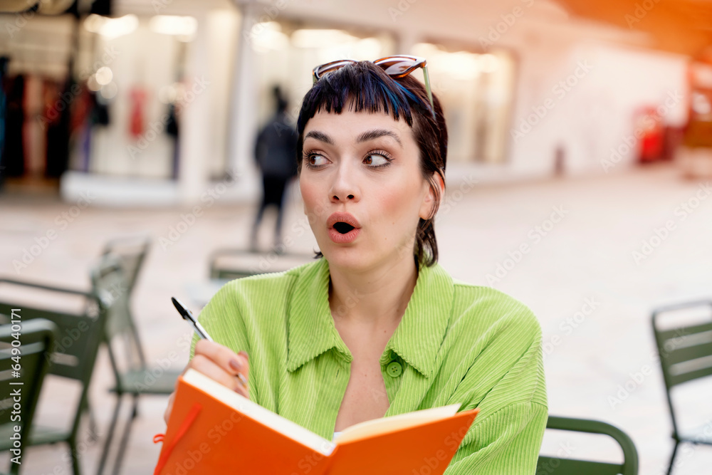 woman student writing in a notebook, making a plan at the street cafe in city. Concept of study hard Lifestyle photo