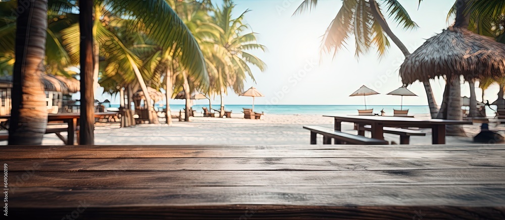 A beach bar in the summertime with a sandy wooden desk in front