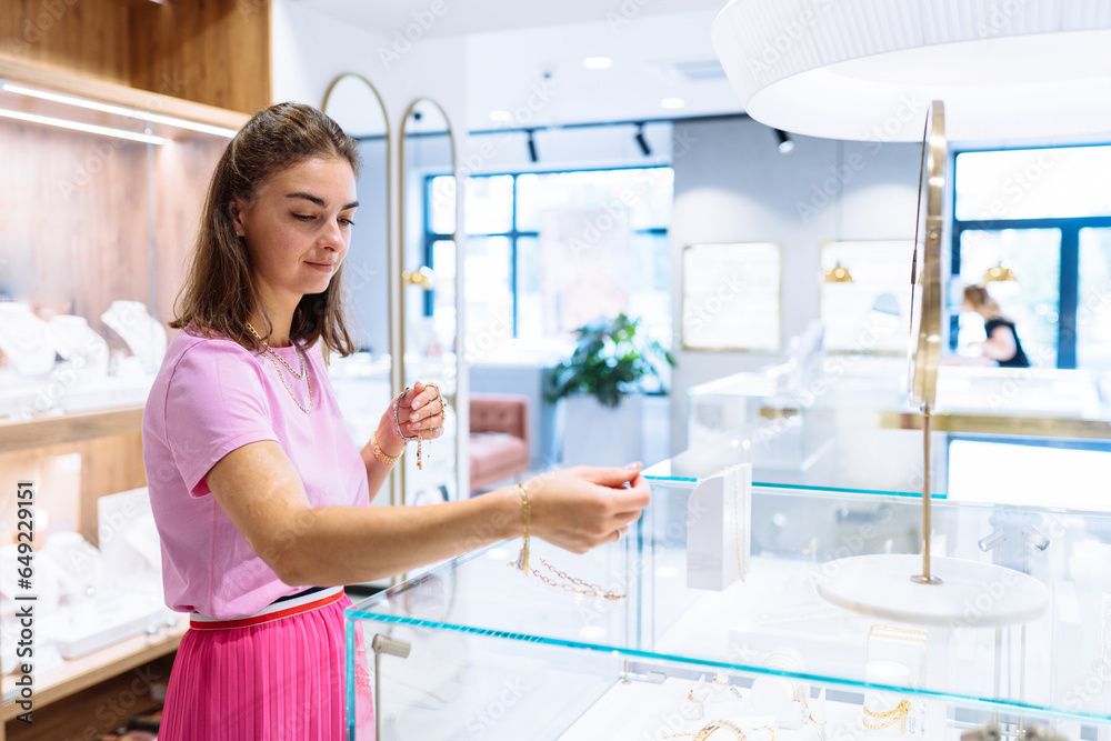 Consumerism, sale, purchases, shopping, lifestyle concept. Beautiful attractive model woman trying and buying jewelry in jewelry store.