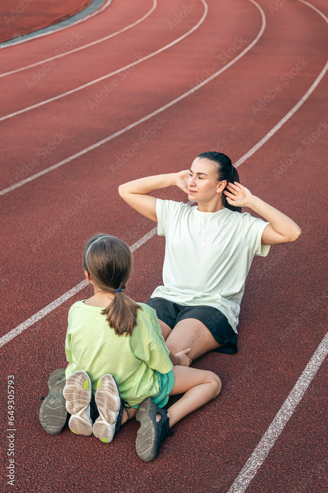 Mother and daughter go in for sports outdoors at the stadium.