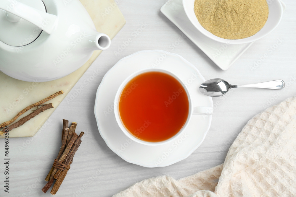 Aromatic licorice tea in cup served on white wooden table, flat lay