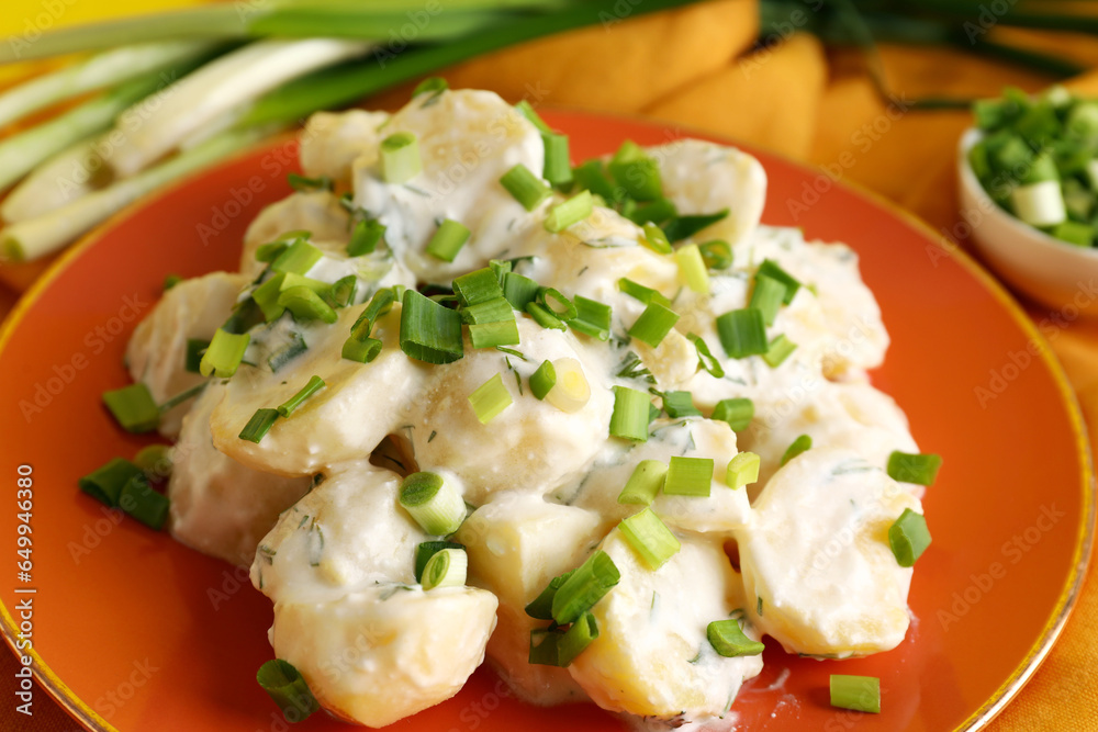 Plate of tasty Potato Salad with greens on table, closeup