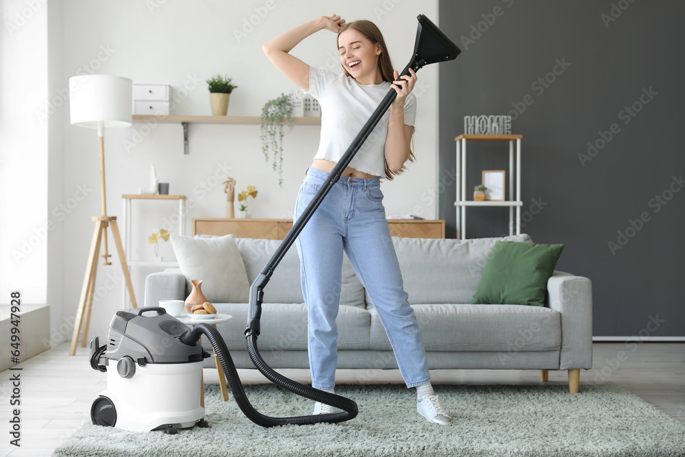 Young woman with vacuum cleaner singing at home