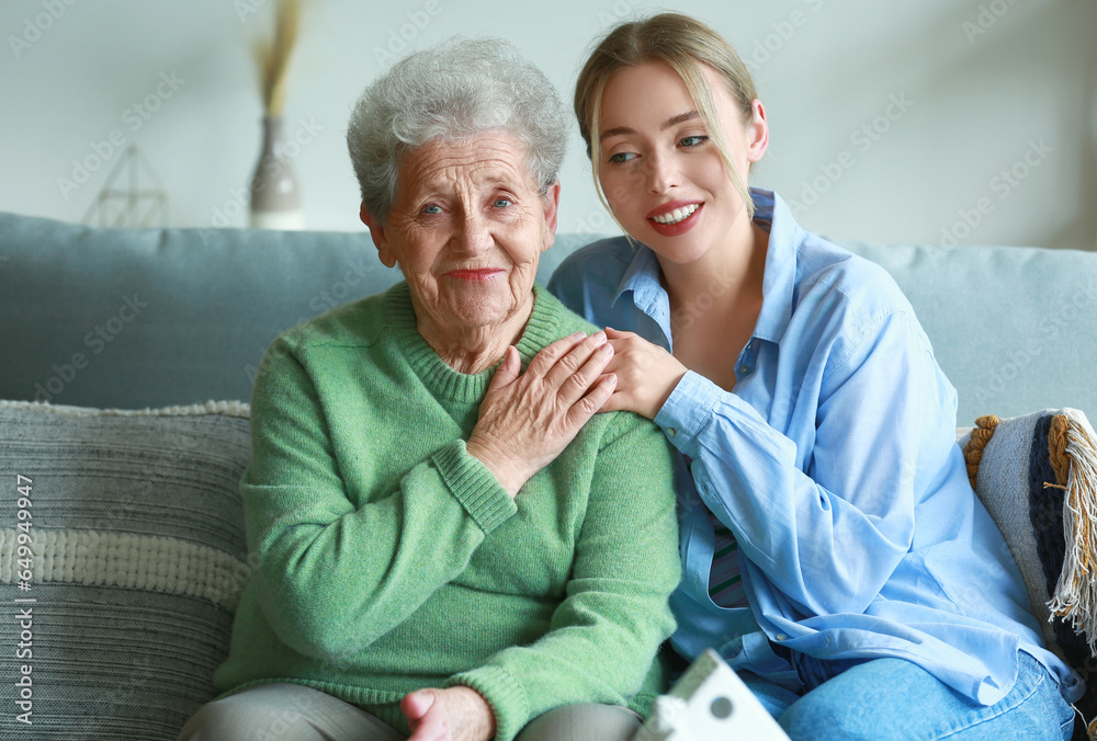 Young woman and her grandmother hugging at home