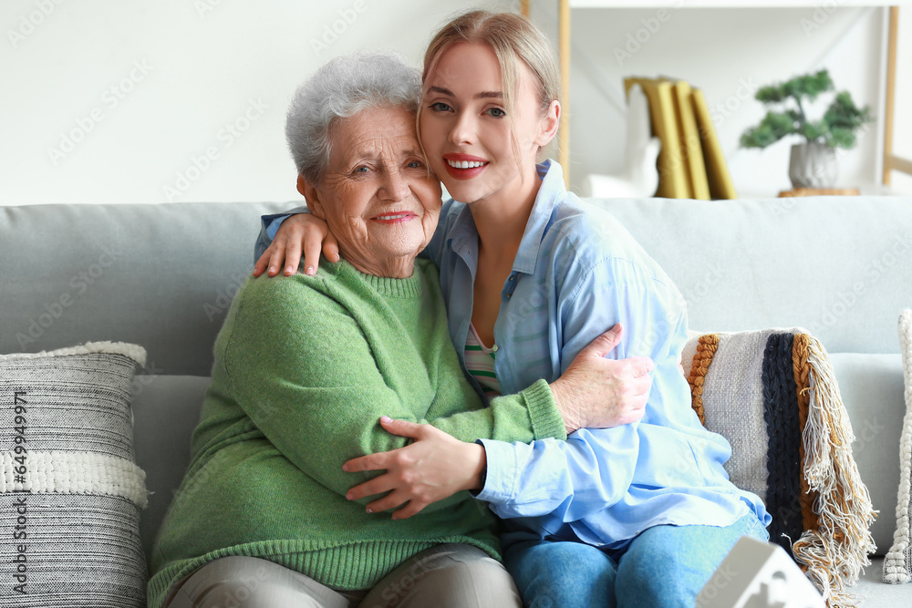 Young woman and her grandmother hugging at home