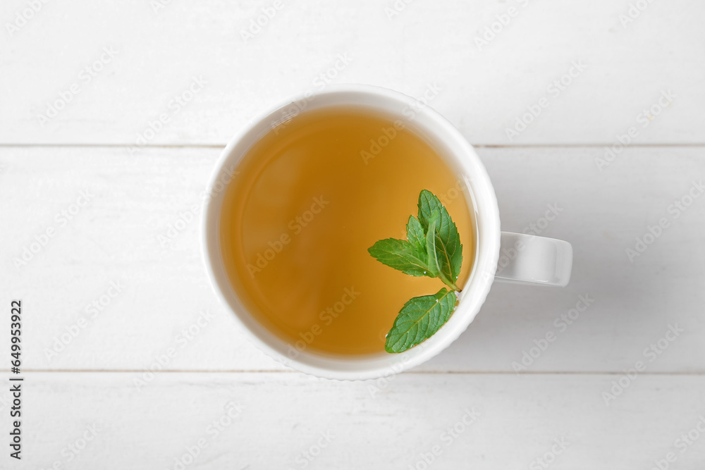 Cup of fresh mint tea on white wooden background