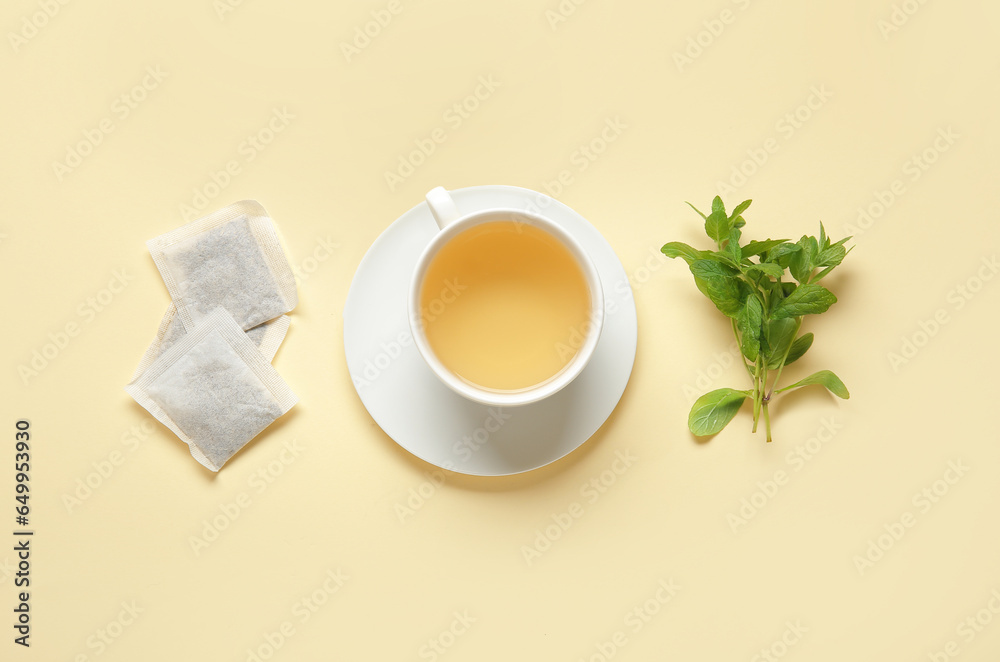 Cup of fresh mint tea on pale yellow background