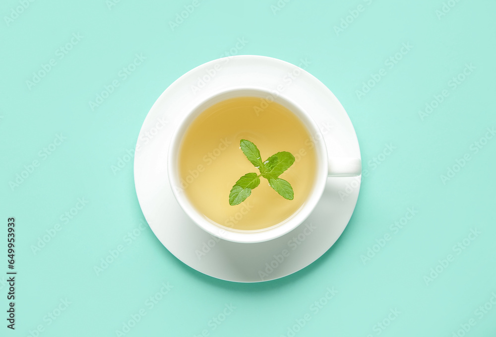 Cup of fresh mint tea on turquoise background