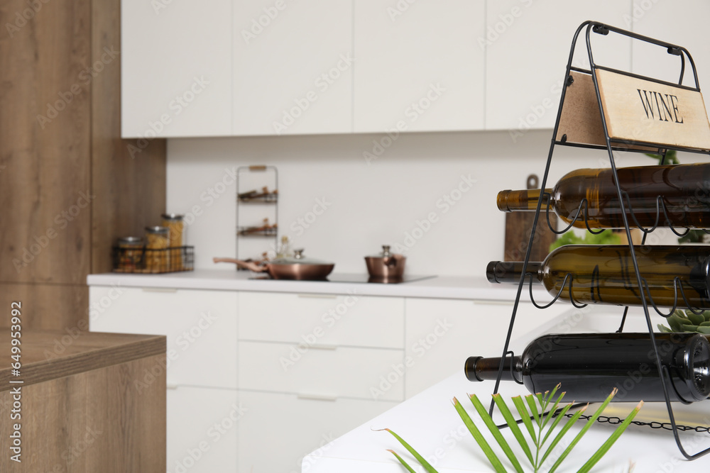 Rack with wine bottles on white countertop in modern kitchen