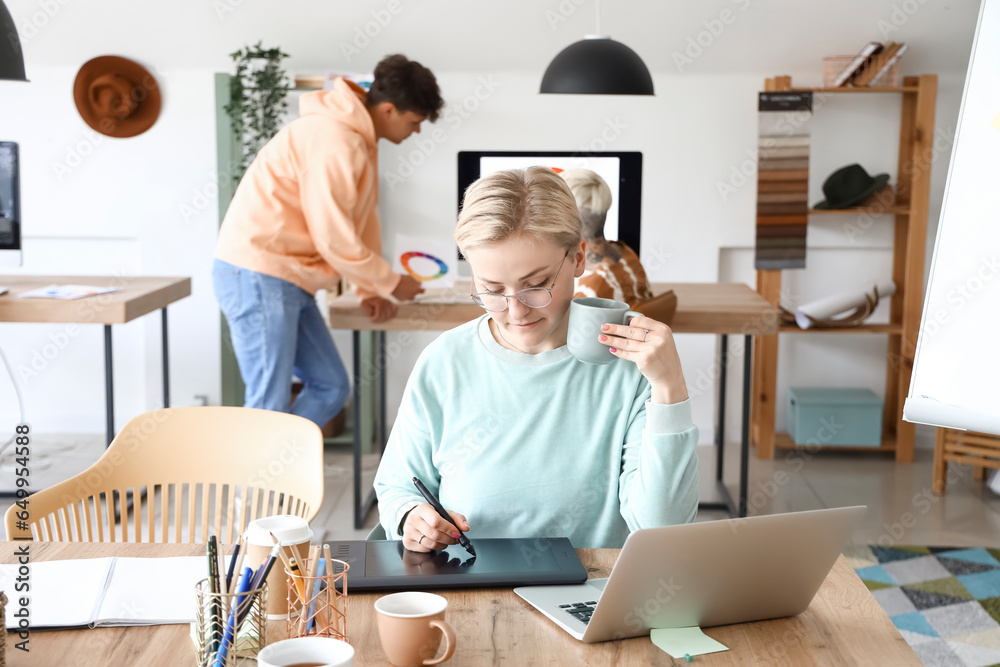 Female graphic designer working with tablet at table in office