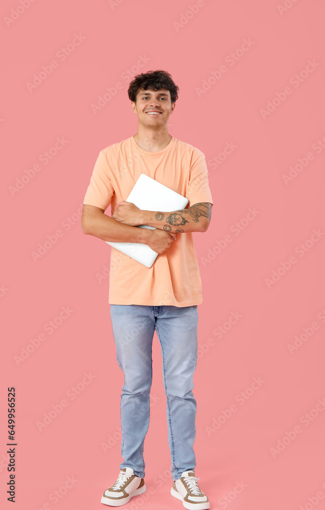 Male programmer with computer on pink background