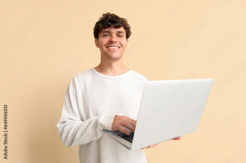 Male programmer working with laptop on beige background