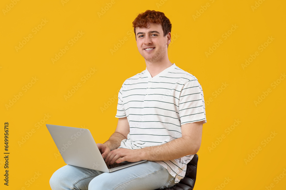 Male programmer working with laptop on yellow background