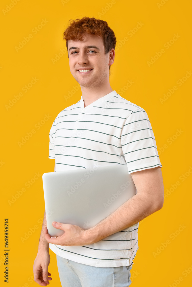 Male programmer with laptop on yellow background