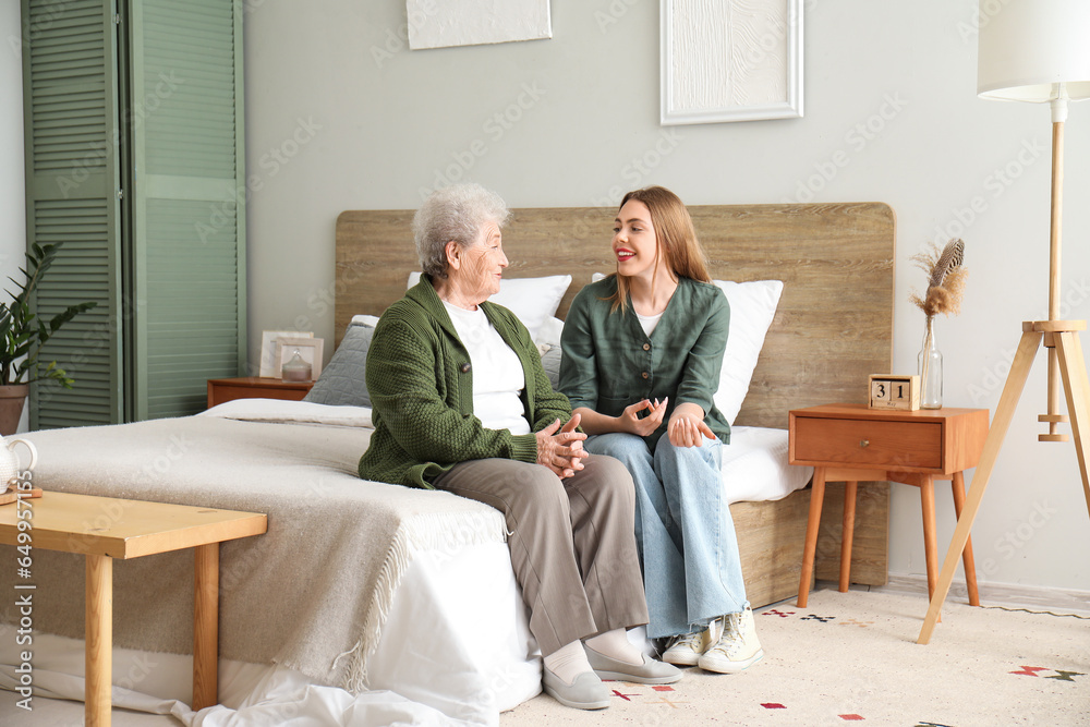 Young woman with her grandmother sitting in bedroom