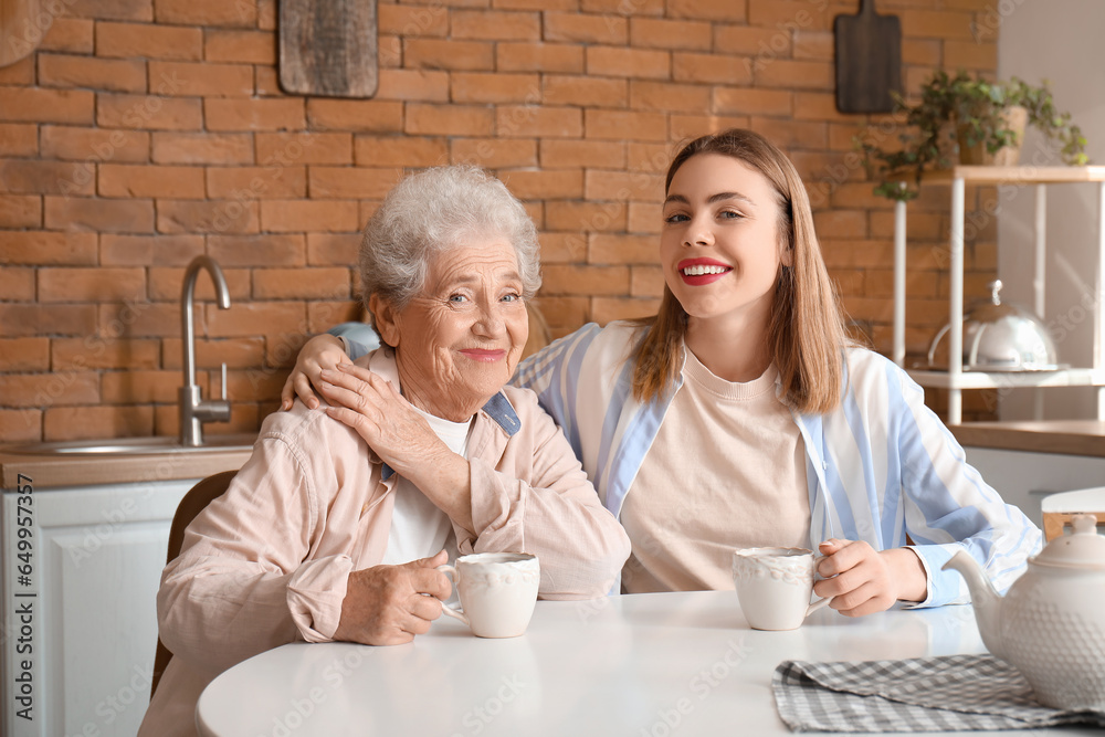 Young woman with her grandmother hugging in kitchen