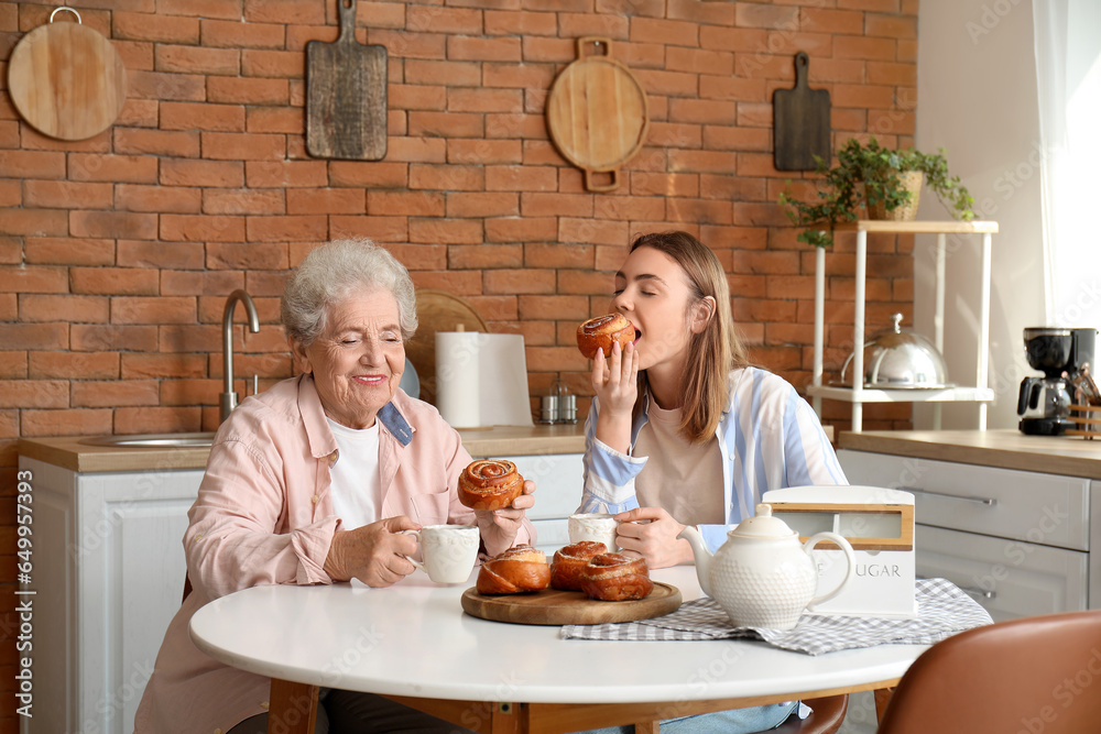 Young woman with her grandmother eating buns in kitchen