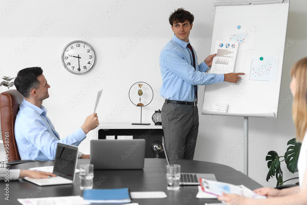 Male business consultant giving presentation to his colleagues in office