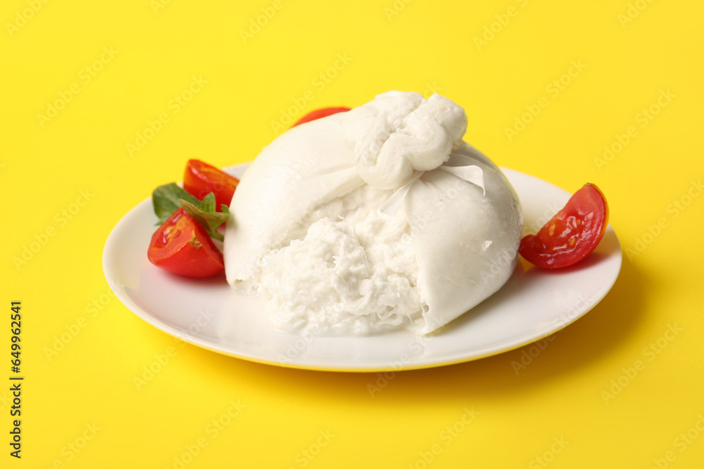 Plate with tasty Burrata cheese on yellow background