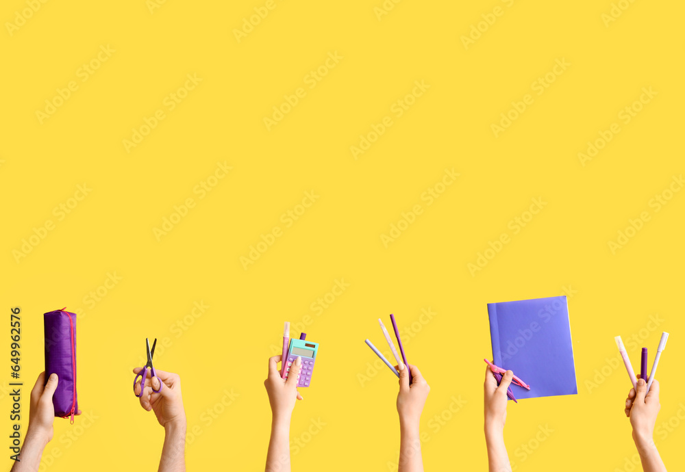 Hands with school supplies on yellow background