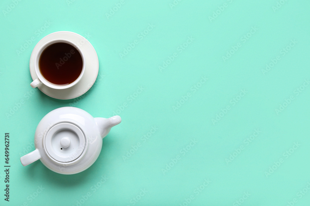 Cup of tea and teapot on color background