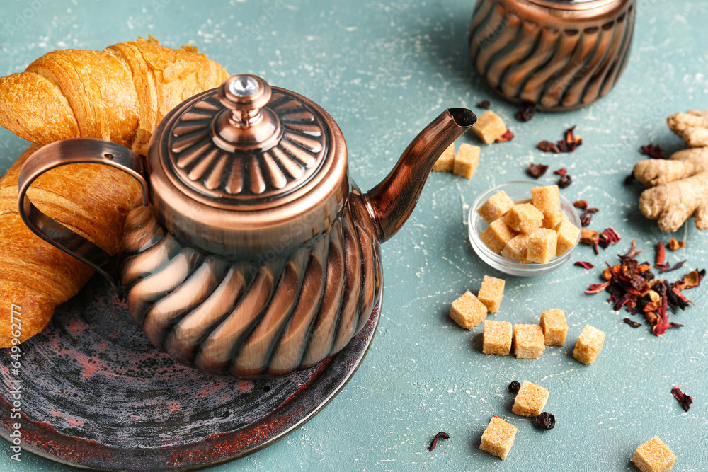 Composition with teapot, sugar and tasty croissants on color background