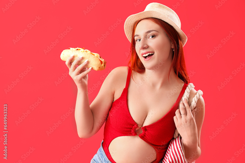 Beautiful young woman with beach bag and hot dog on red background