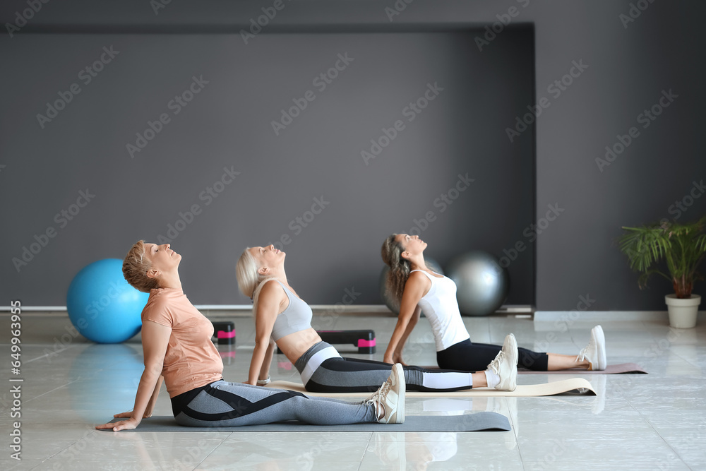 Sporty mature women practicing yoga in gym