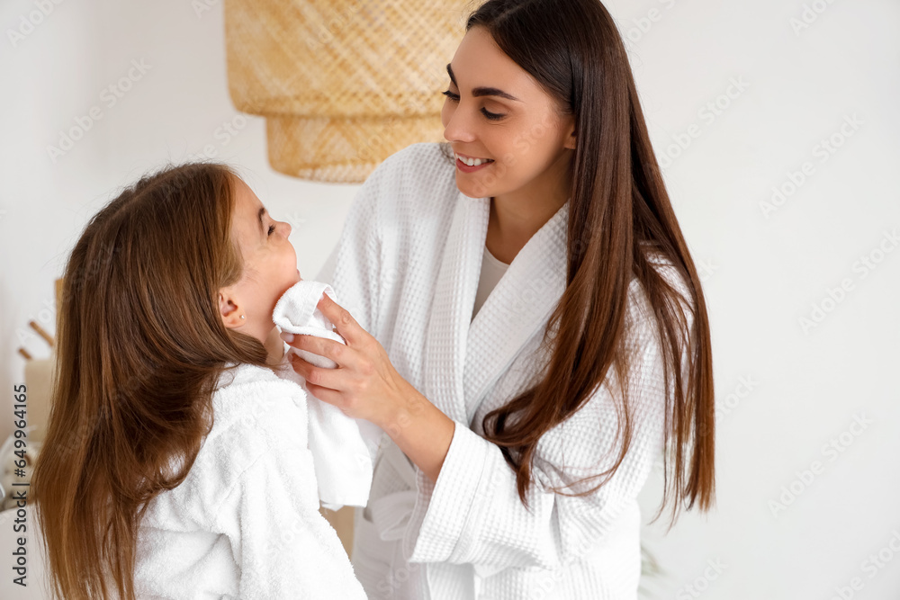 Happy mother wiping her little daughters face in bathroom