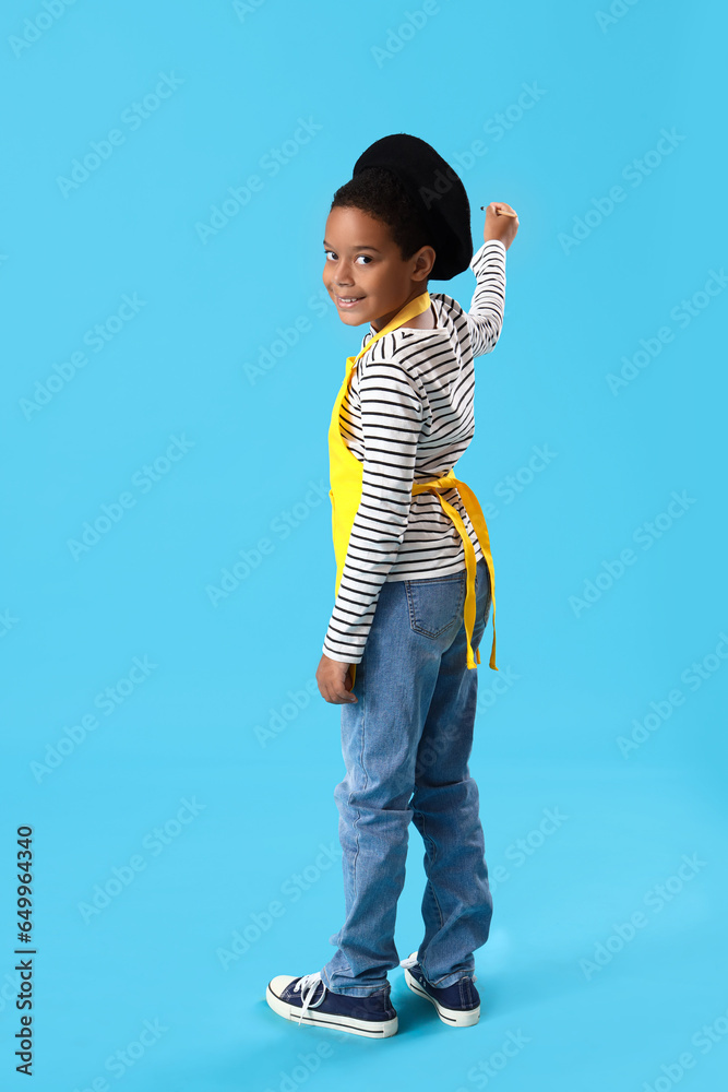 Little African-American boy with paint brush on blue background