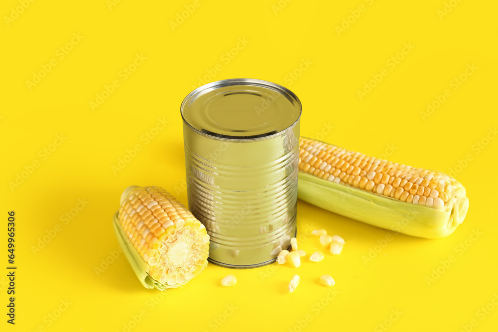 Fresh corn cobs and tin can with seeds on yellow background