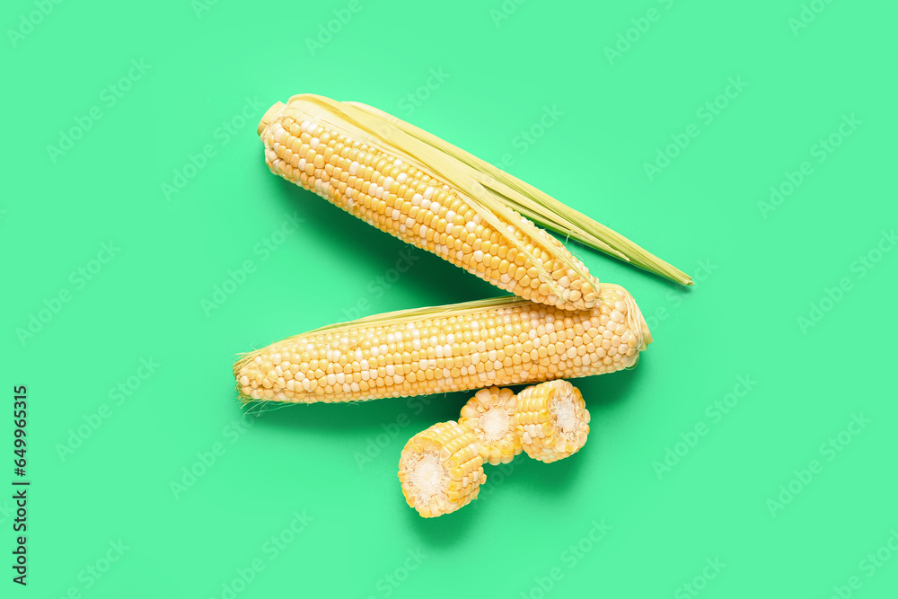 Fresh corn cobs on green background