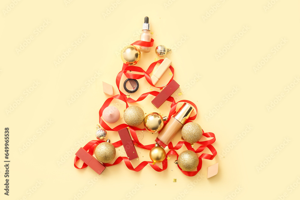 Christmas tree made of golden balls, makeup cosmetics and ribbon on beige background