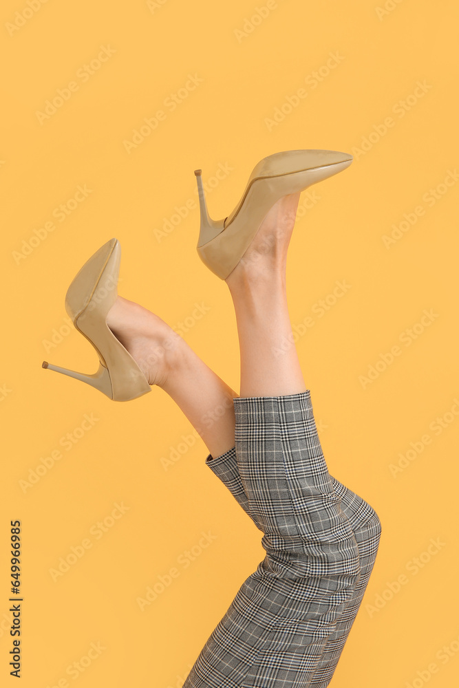 Female legs in beautiful high heeled shoes on color background, closeup