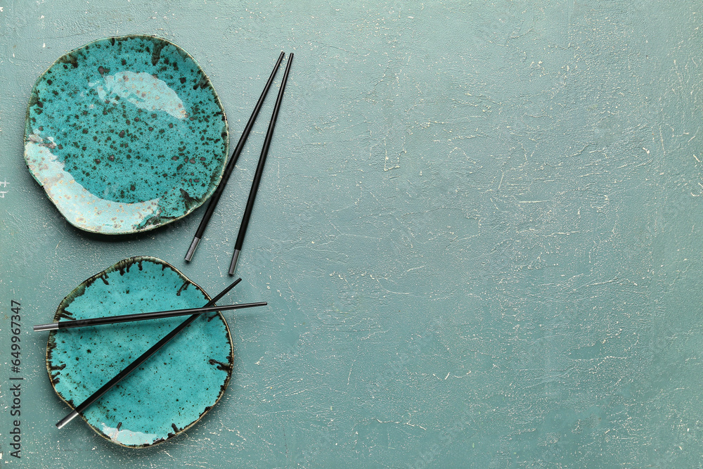 Chinese chopsticks and plates on color background