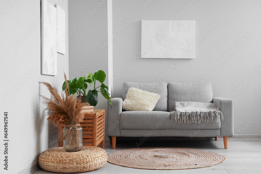 Interior of modern living room with paintings, grey sofa and houseplant