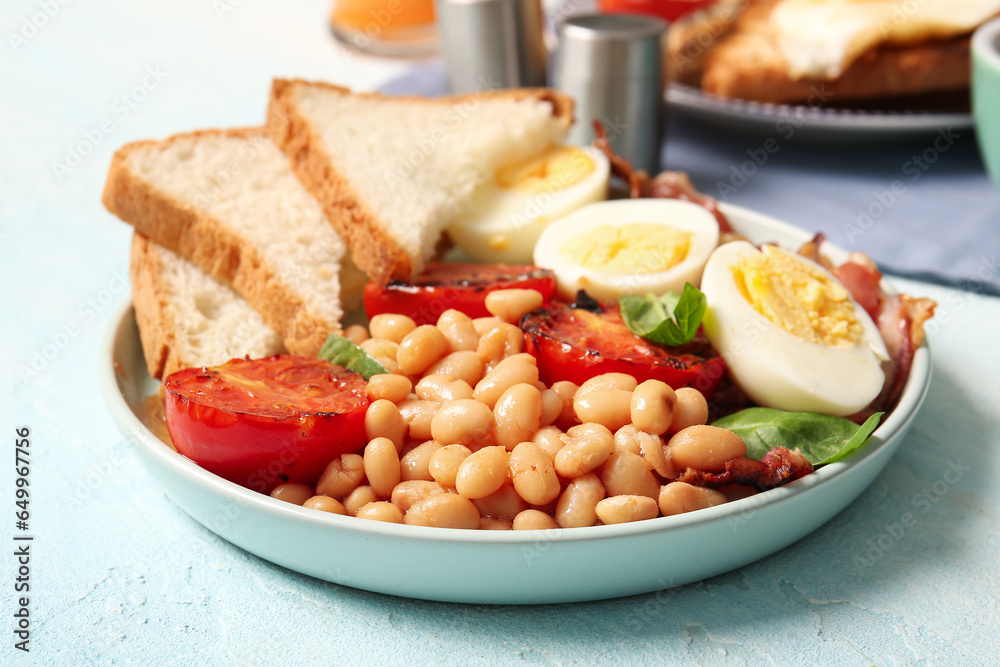 Plate of tasty English breakfast with boiled eggs on blue background