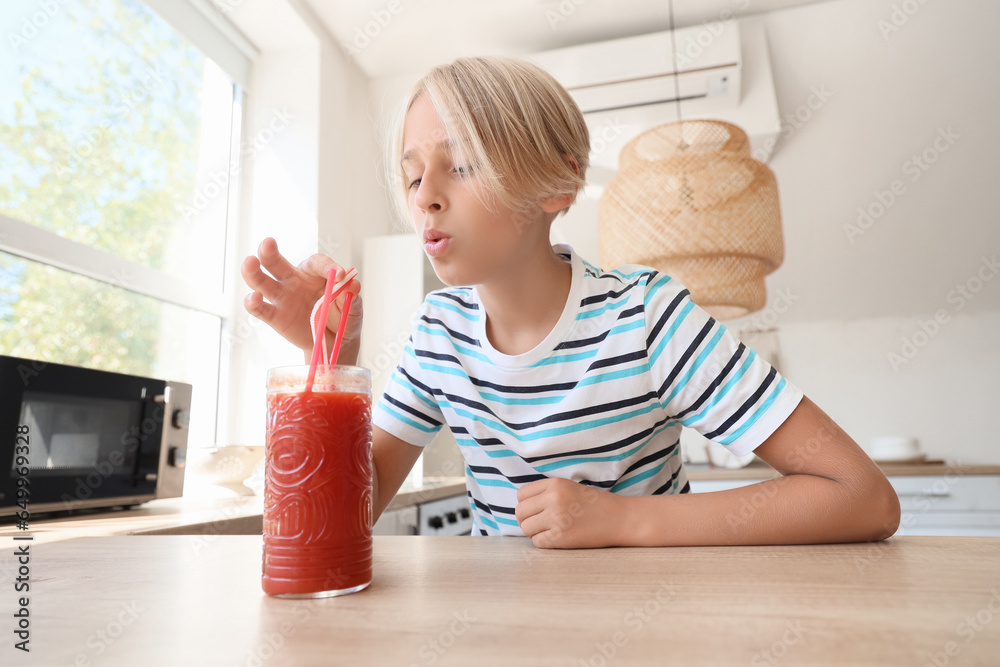 Little boy with glass of red juice in kitchen