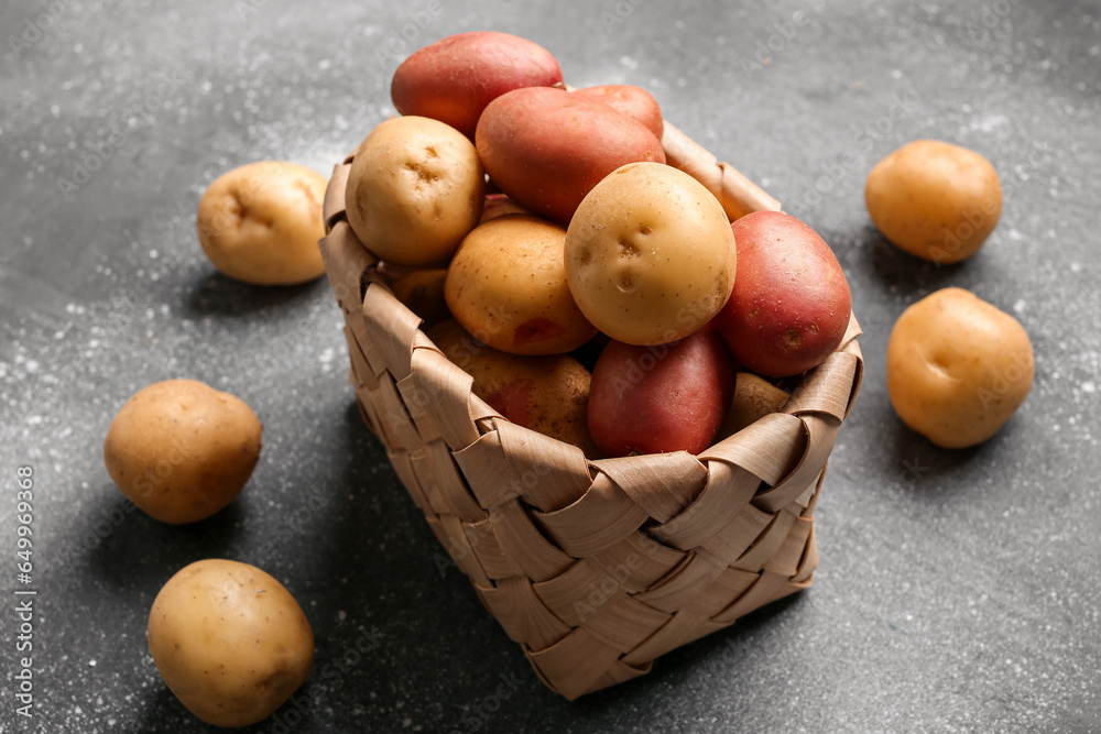 Wicker bowl with fresh raw potatoes on grey background