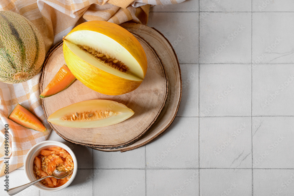 Wooden boards with tasty ripe melons on white tile background