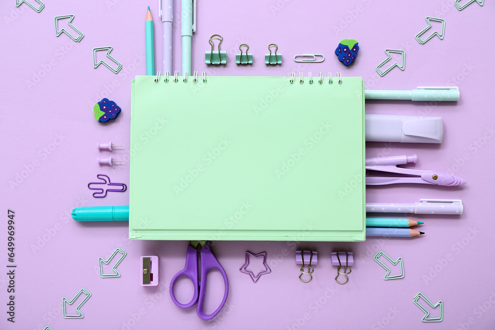 Notebook with different stationery supplies on lilac background