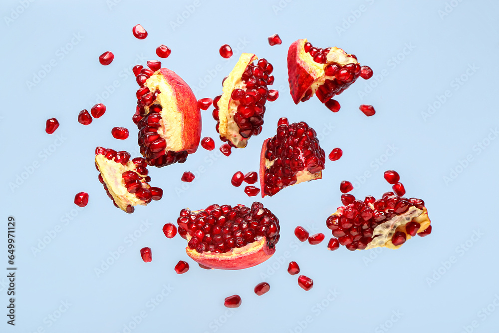 Flying fresh pomegranates with seeds on blue background