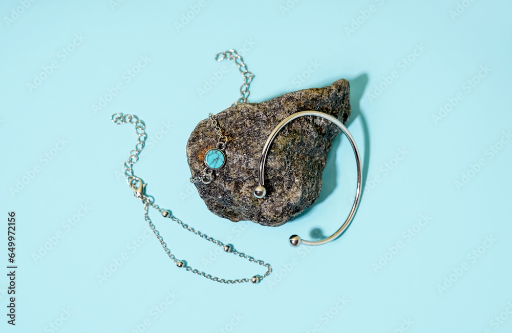 Rock with different beautiful silver bracelets on blue background