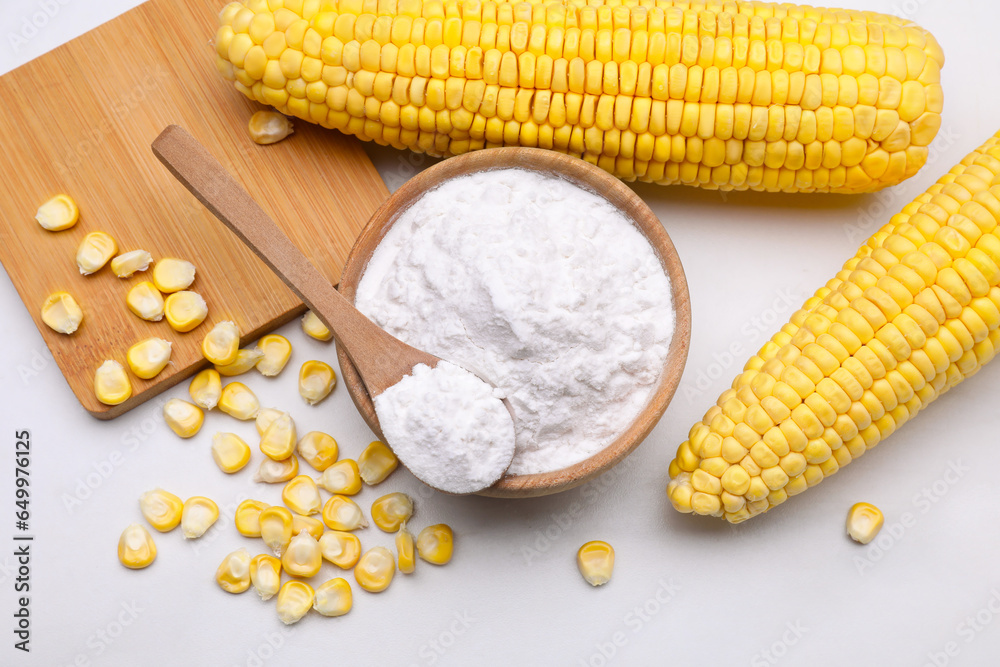 Bowl with corn starch, ripe cobs and kernels on white marble table, flat lay