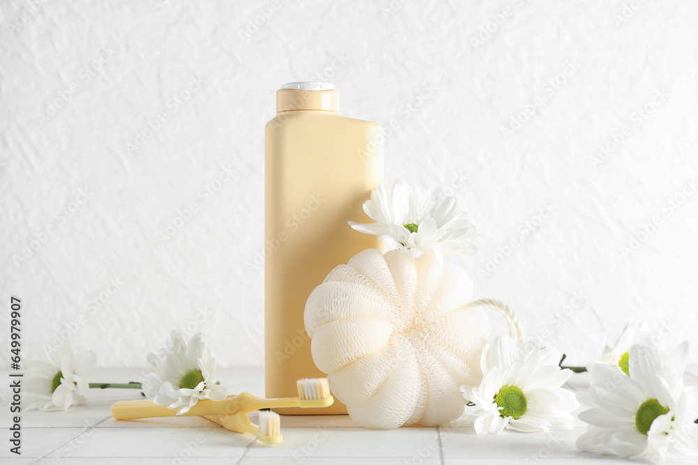 Composition with bath supplies and chamomile flowers on table against light background