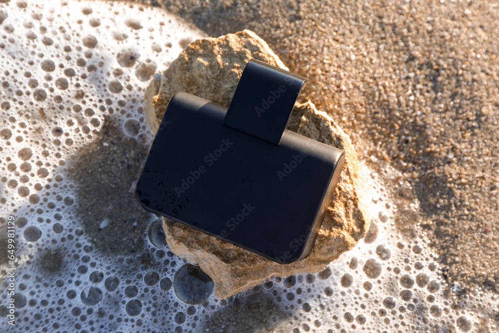 Bottle of elegant perfume on sea shore