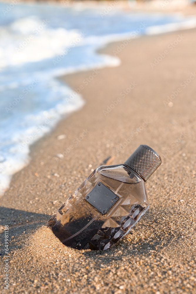 Bottle of elegant perfume on sea shore