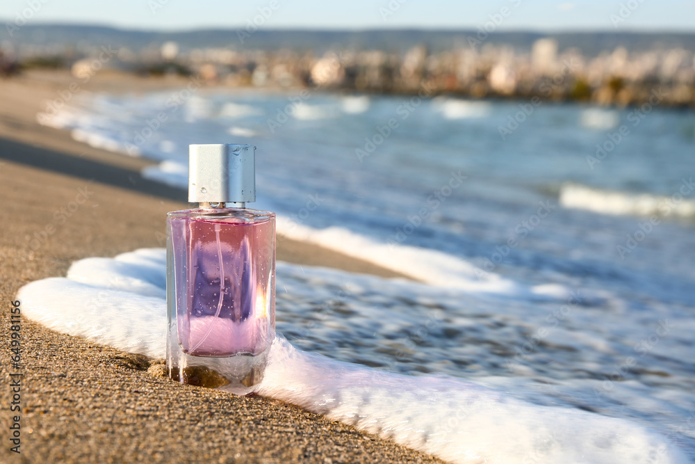 Bottle of aromatic perfume on sea shore, closeup