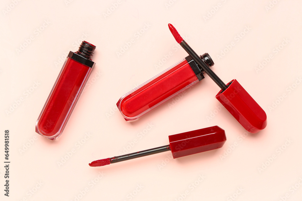 Different pink lipsticks with brushes on pink background