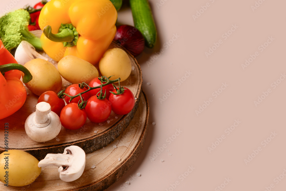 Wooden boards with different fresh vegetables on beige background